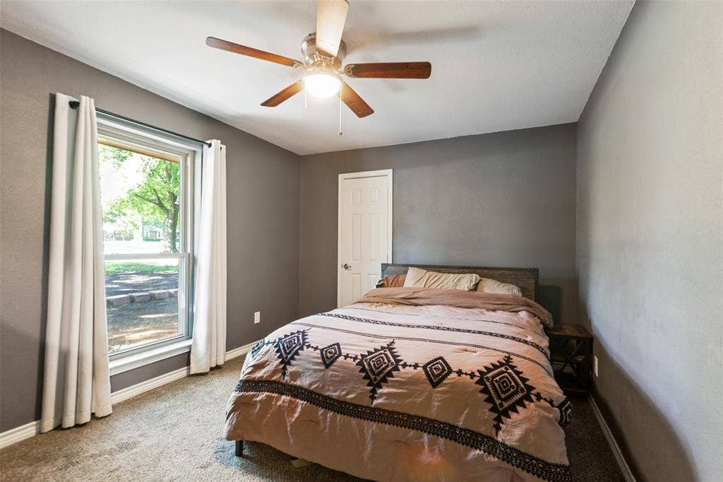 Carpeted flooring, ceiling fan, white trim, and a window with white curtains