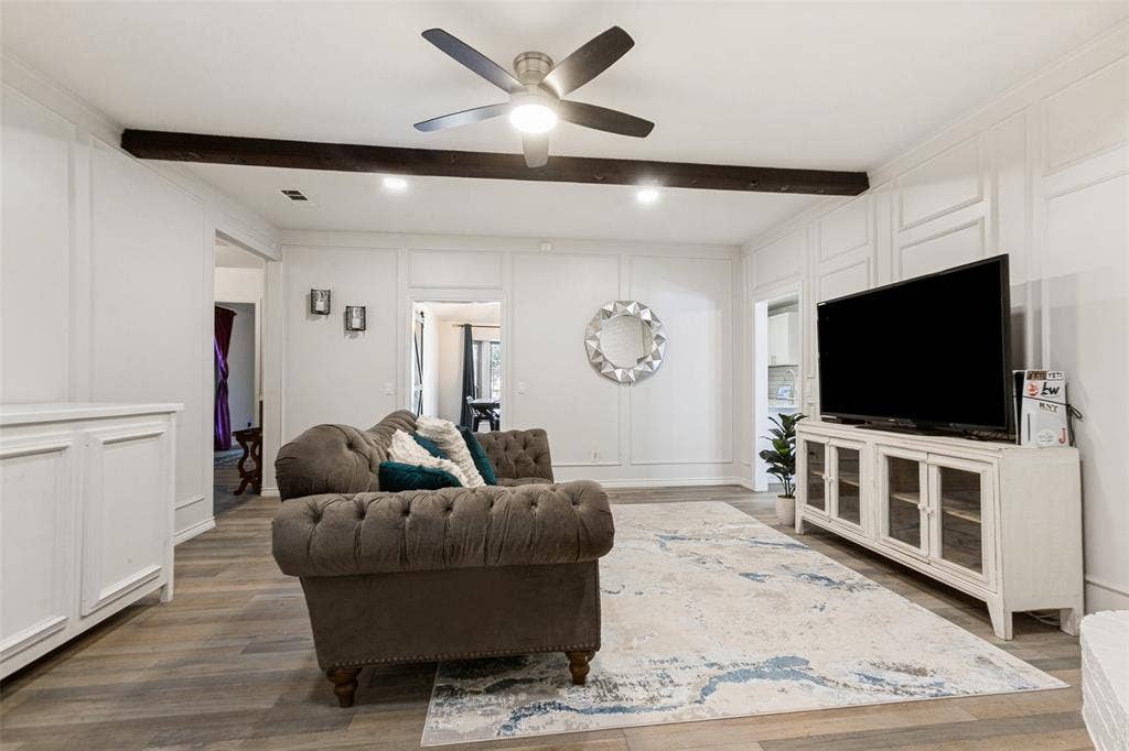 Recessed lighting, wood-finish flooring, accent wall paneling, ceiling fan, and exposed ceiling beam