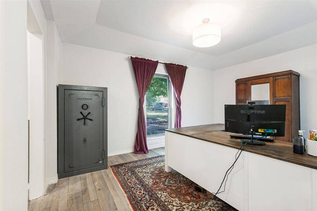 Tray ceiling, wood-finish flooring, built-in desk with wood-finish top, drum pendant light fixture, window with exterior landscaping