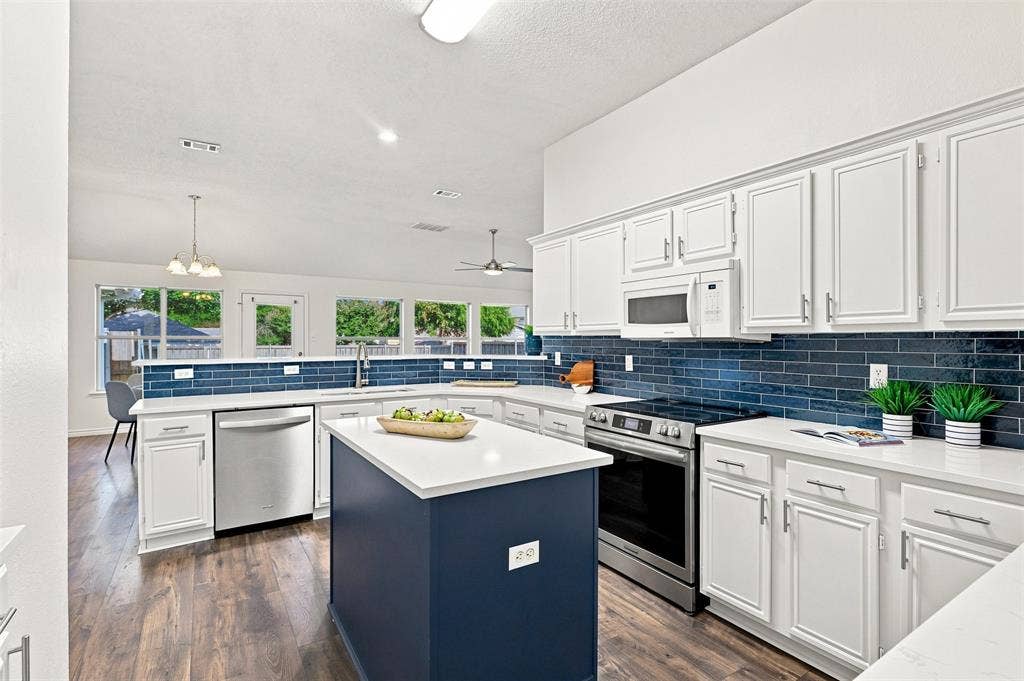 1110 Harvard Lane, Allen, TX 75002 Kitchen featuring white cabinetry, a blue subway tile backsplash, stainless steel appliances, a center island with a white countertop, and wood-finish flooring