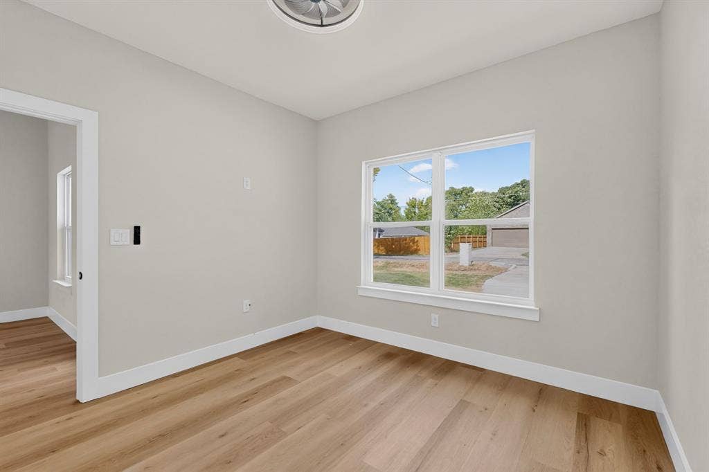 Wood-finish flooring, white window trim, white baseboards, and a ceiling-mounted light fixture