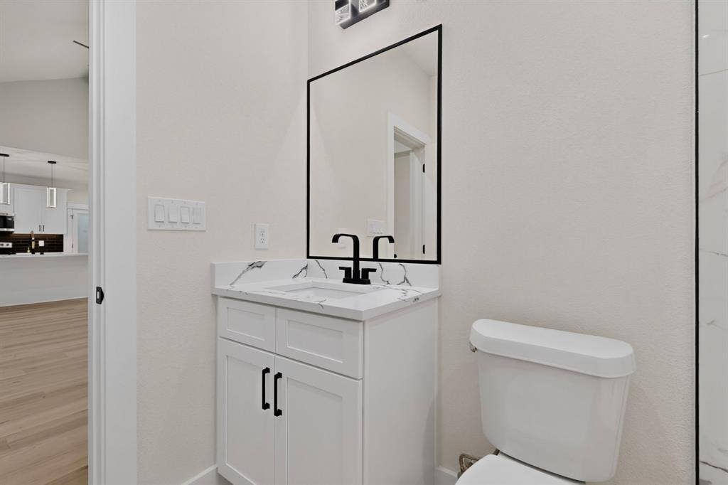 White vanity with matte black hardware, integrated sink, and white countertop