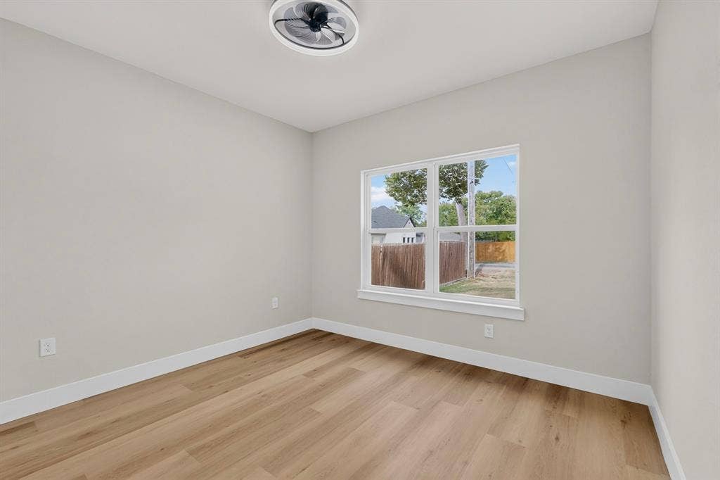 Recessed ceiling light with fan, wood-finish flooring, white walls, and a large window