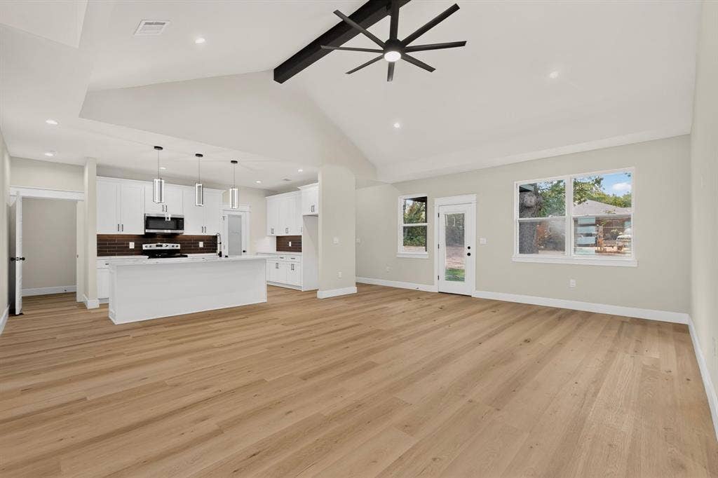 Spacious living area featuring wood-finish flooring and a vaulted ceiling with a modern ceiling fan