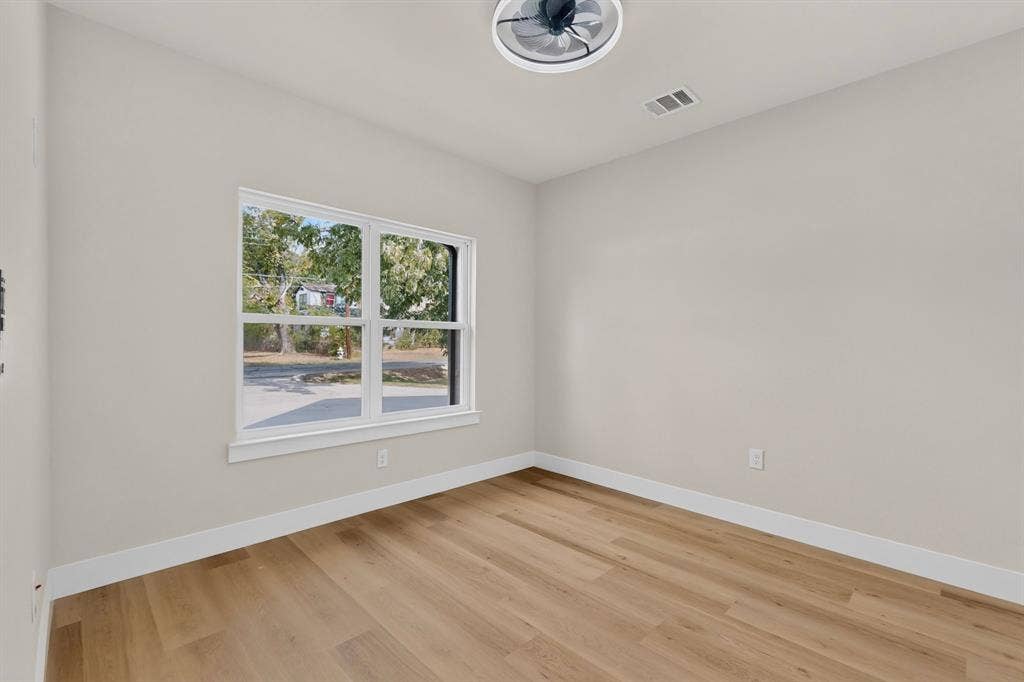 Light-toned walls, wood-finish flooring, and a contemporary ceiling fan