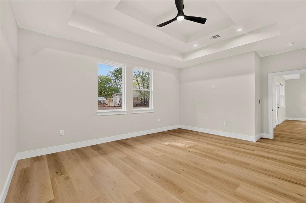 Expansive interior featuring wood-finish flooring, a tray ceiling, and a modern ceiling fan
