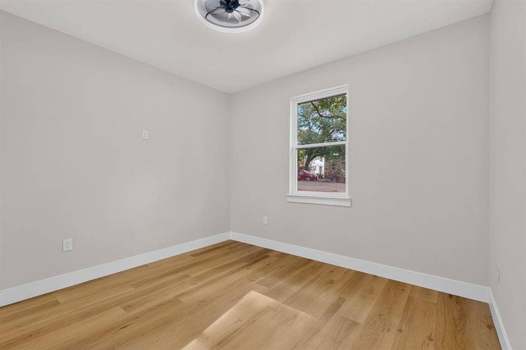Wood-finish flooring, white trim, single window, and a ceiling-mounted light fixture