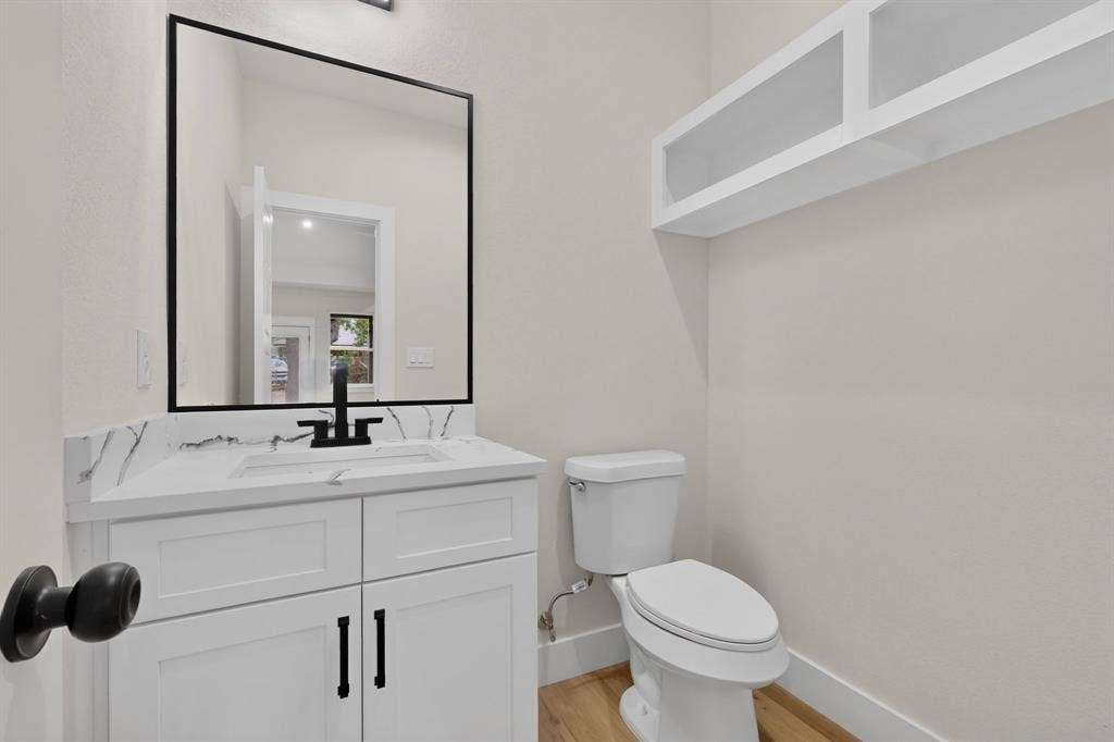 White vanity with a stone-finish countertop, undermount sink, and black wall-mounted faucet