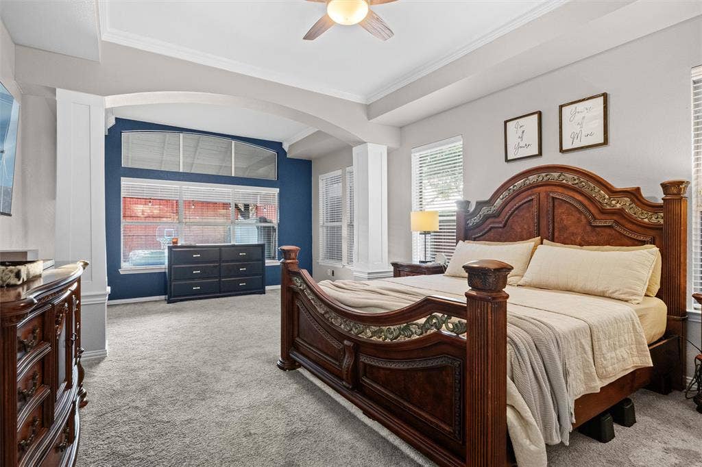 Spacious primary suite featuring a sitting area, tray ceiling, and abundant natural light.