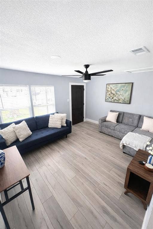 228 Harrison Lane, Hurst, TX 76053 Spacious area with wood-finish flooring, multiple windows with blinds, a ceiling fan, and a solid black interior door