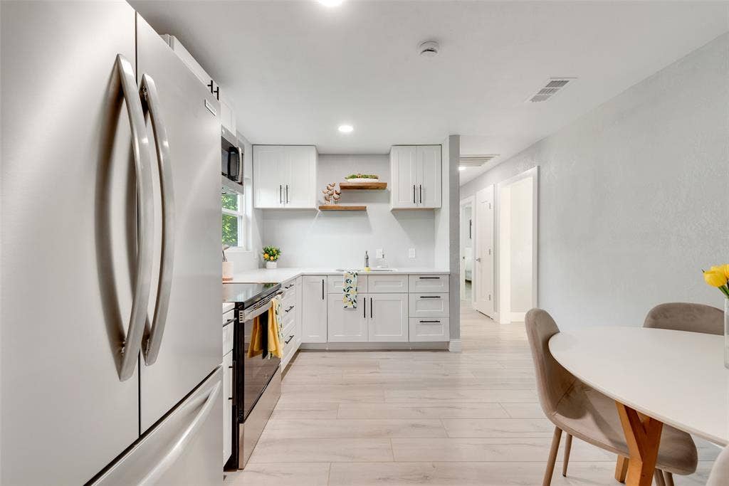 228 Harrison Lane, Hurst, TX 76053 Modern kitchen featuring stainless steel appliances, white cabinetry, light-colored countertops, and wood-finish flooring