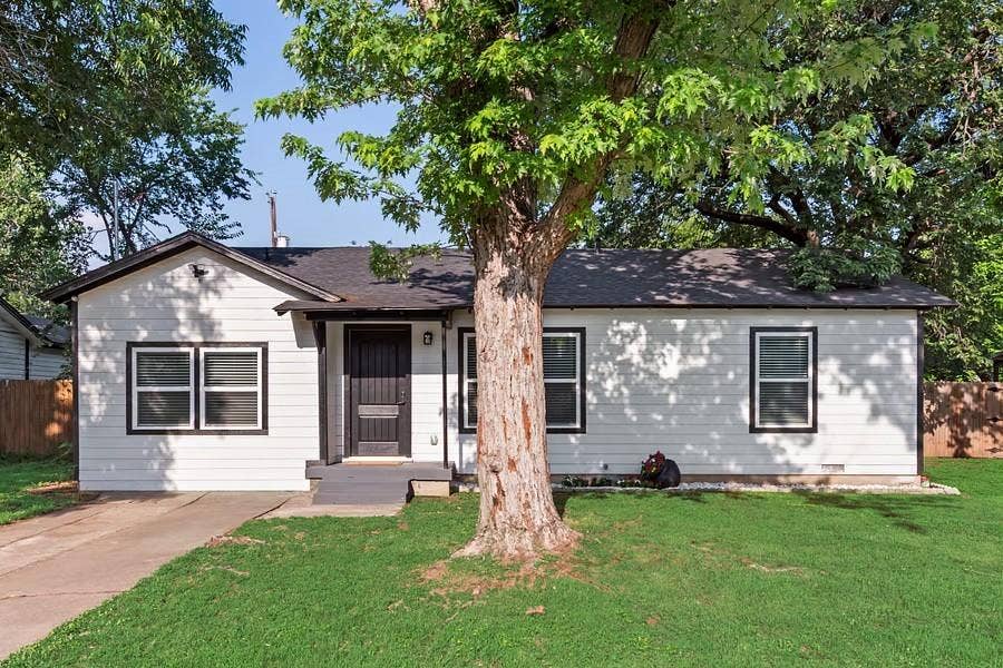 228 Harrison Lane, Hurst, TX 76053 White siding exterior with dark trim accents, a front porch entry, and a dark asphalt shingle roof