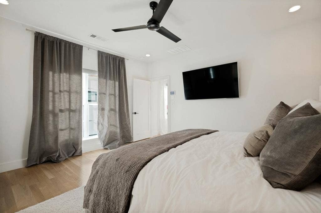 Recessed ceiling lighting, a contemporary ceiling fan, and wood-finish flooring