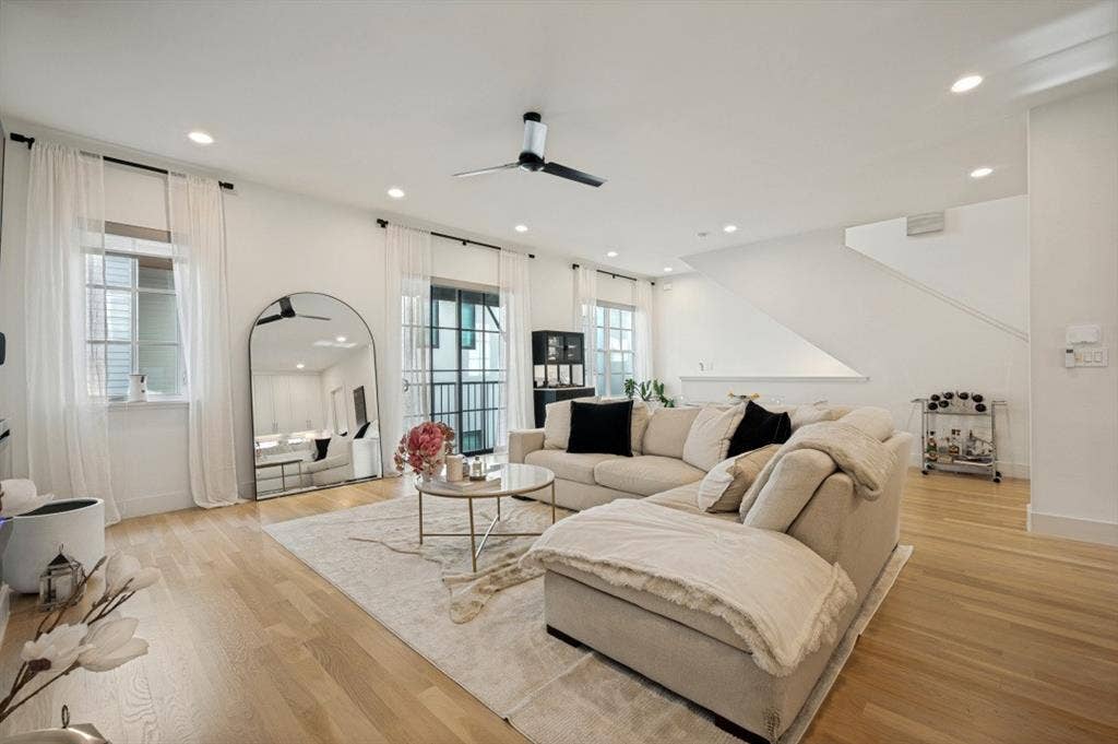 Recessed lighting, light wood-finish flooring, staircase, ceiling fan, and large windows with transom details
