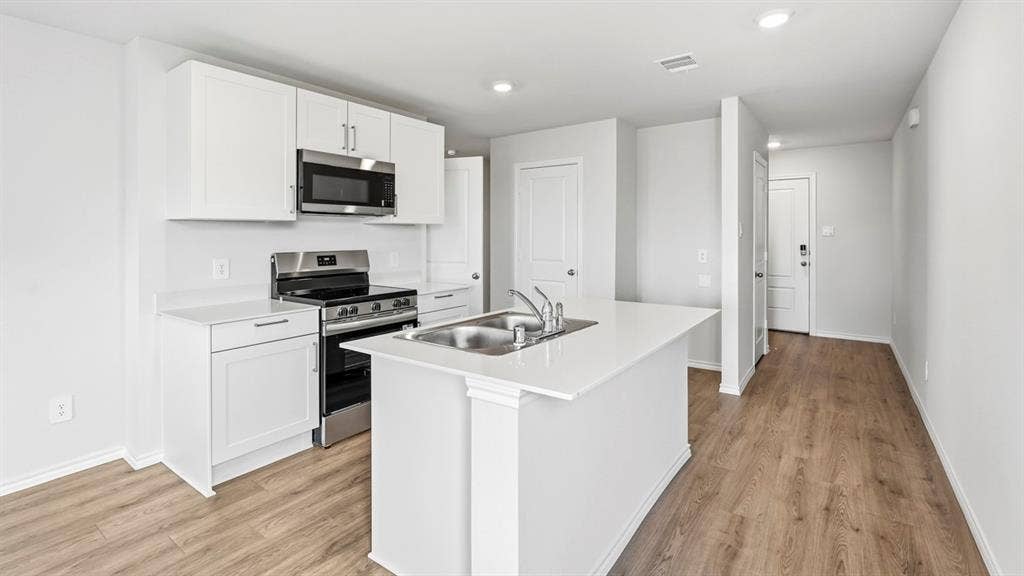 3327 Twilight Trail, Talty, TX 75126 Kitchen featuring white cabinetry, stainless steel appliances, a kitchen island with an integrated sink, white countertops, and wood-finish flooring