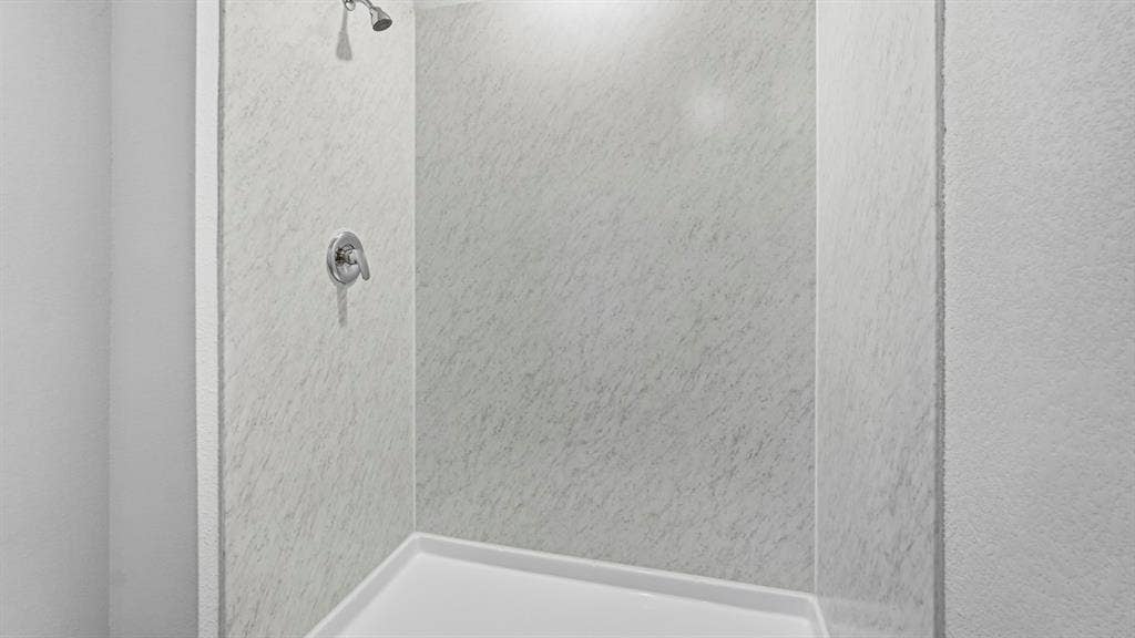 3327 Twilight Trail, Talty, TX 75126 Enclosed shower with a white acrylic base and textured wall panels, featuring a chrome shower head and control handle