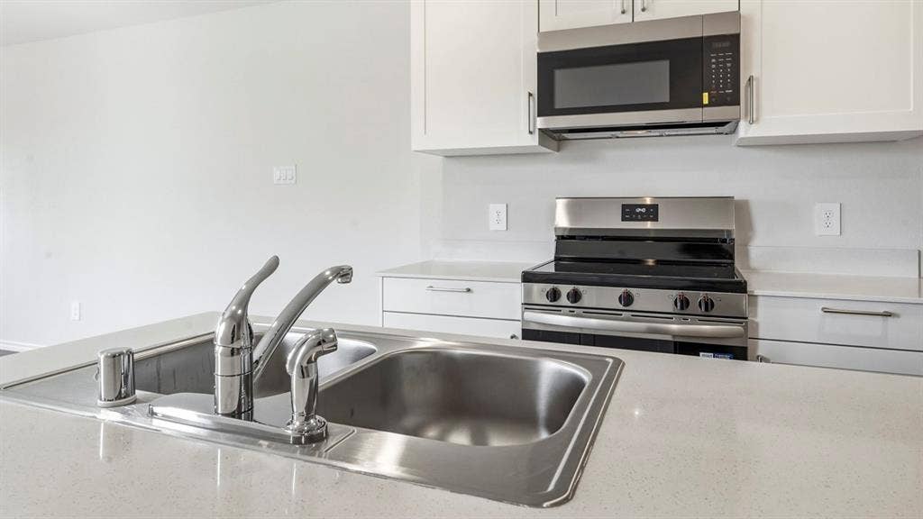 3327 Twilight Trail, Talty, TX 75126 Stainless steel double basin sink with chrome faucet, white cabinetry, integrated stainless steel microwave, and stainless steel range