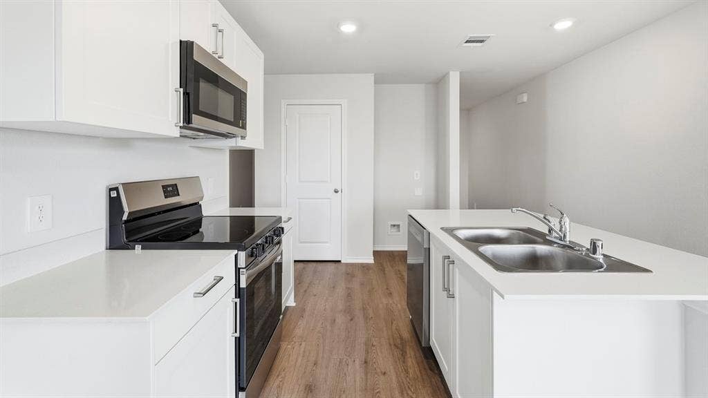 3327 Twilight Trail, Talty, TX 75126 Bright kitchen featuring white cabinetry, stainless steel appliances, wood-finish flooring, white countertops, and recessed lighting