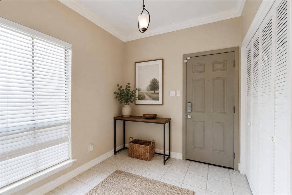 9400 Doliver Drive, #59, Houston, TX 77063 Entryway featuring tile flooring, crown molding, a paneled door, and louvered closet doors