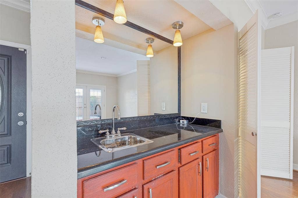 9400 Doliver Drive, #59, Houston, TX 77063 Built-in bar area featuring a stainless steel sink, dark countertop, and warm-toned cabinetry
