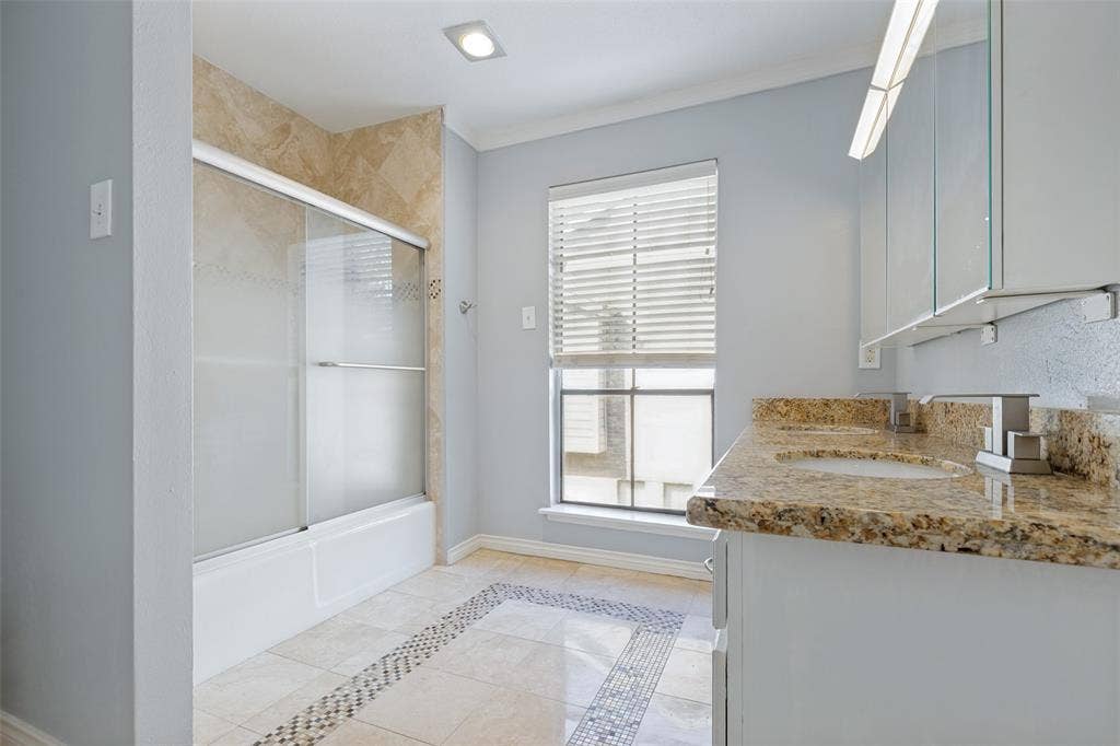 9400 Doliver Drive, #59, Houston, TX 77063 Dual vanity with stone countertop, tile flooring with decorative inlay, built-in bathtub with sliding glass doors, and recessed lighting