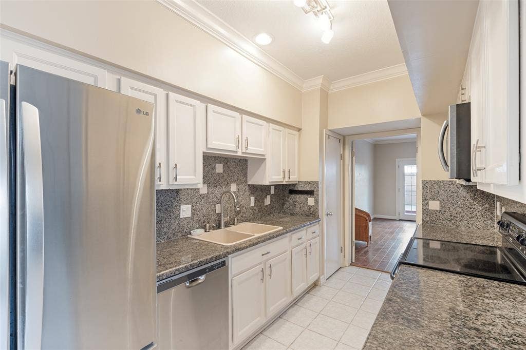 9400 Doliver Drive, #59, Houston, TX 77063 Kitchen featuring white cabinetry, dark stone countertops, stainless steel appliances, and a tile backsplash