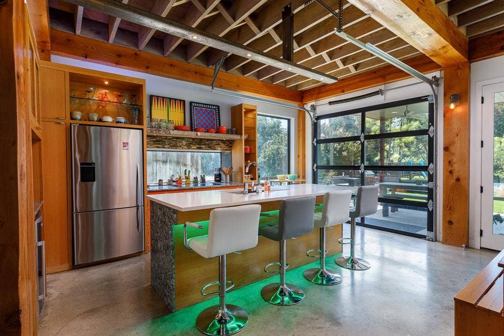6448 County Road 437, Princeton, TX 75407 Exposed wood beam ceiling, concrete flooring, full-light roll-up door, stainless steel refrigerator, and built-in wood cabinetry