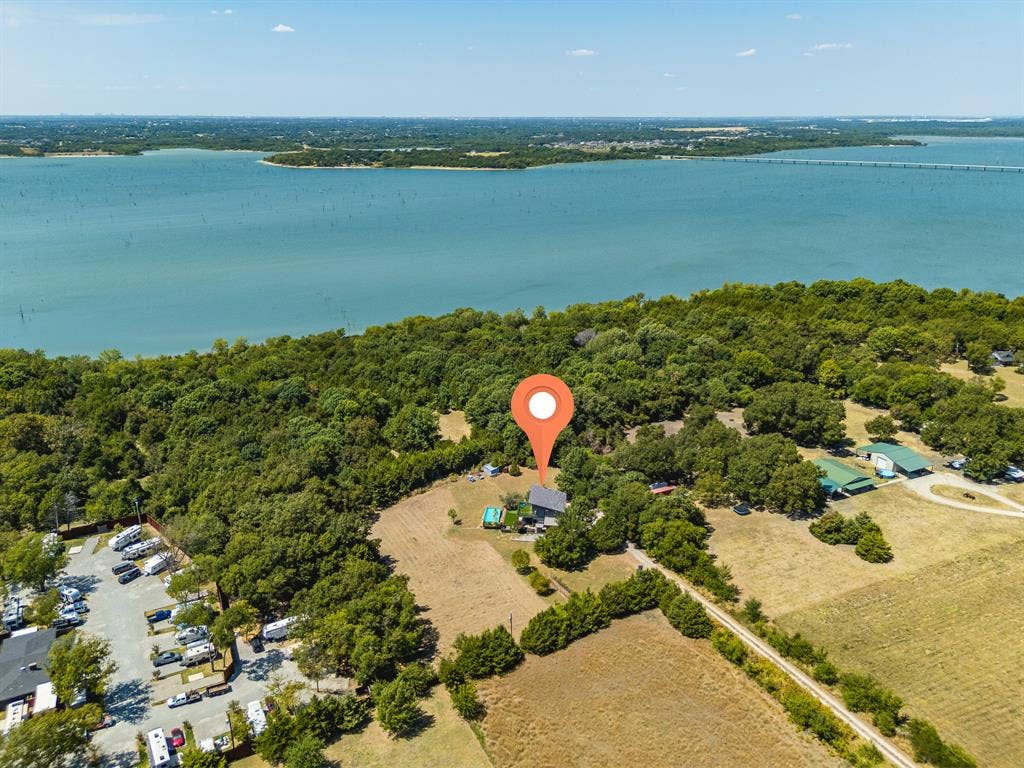 6448 County Road 437, Princeton, TX 75407 Expansive waterfront property with a residential structure, mature trees, and a paved road