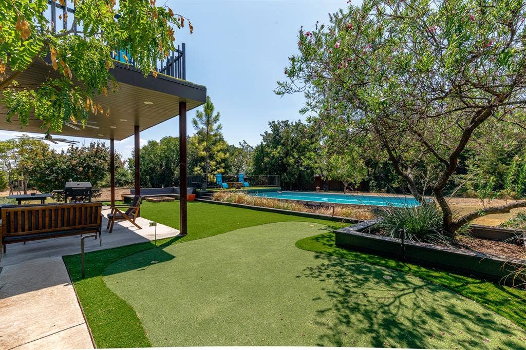 6448 County Road 437, Princeton, TX 75407 Covered patio with ceiling fan, artificial turf putting green, swimming pool, mature trees, and 1 of 5 puttin greens