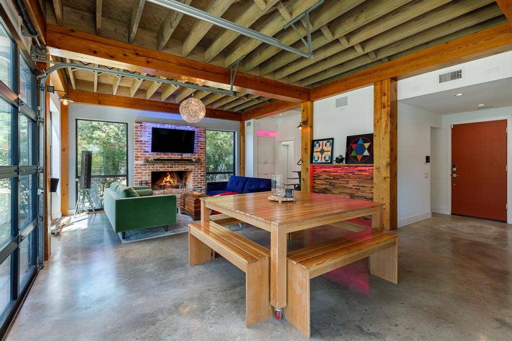 6448 County Road 437, Princeton, TX 75407 Exposed wood beam ceiling, brick fireplace, concrete flooring, full-light glass garage door, and a built-in wood accent wall