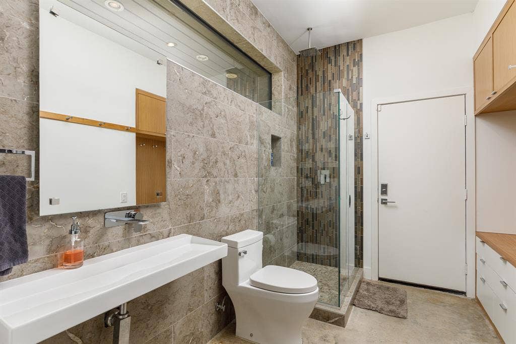 6448 County Road 437, Princeton, TX 75407 Wall-mounted rectangular sink, glass-enclosed shower, tiled shower surround, recessed shower niche, and custom wood cabinetry