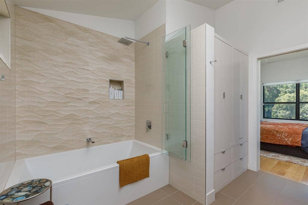 6448 County Road 437, Princeton, TX 75407 Bathtub with wall-mounted faucet and showerhead, glass shower partition, and built-in storage cabinetry