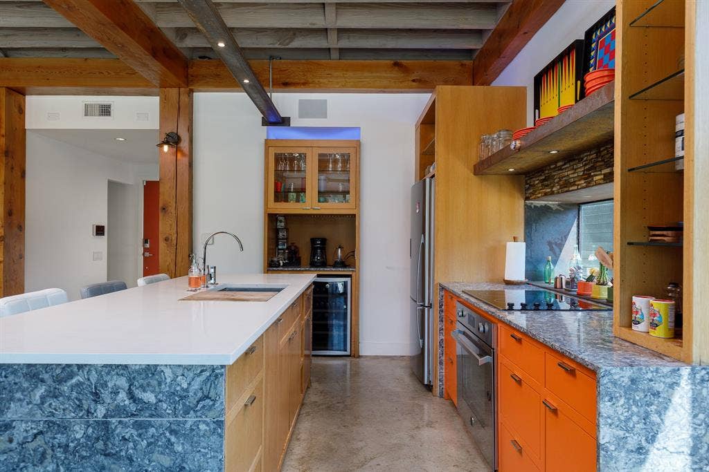 6448 County Road 437, Princeton, TX 75407 Exposed wood beams, concrete flooring, stainless steel appliances, white countertop island, and vibrant orange cabinetry