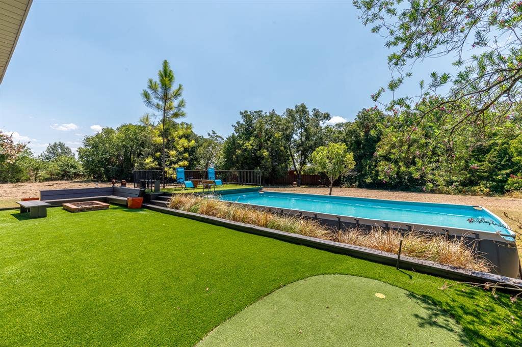 6448 County Road 437, Princeton, TX 75407 Backyard featuring an in-ground swimming pool, artificial turf, putting green, built-in wooden seating, a fire pit, and 1 of 5 puttin greens