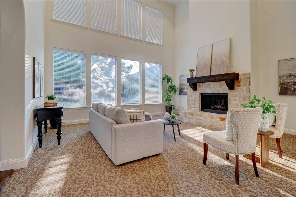 11559 Ashley Lane, Frisco, TX 75035 Living area featuring a stone fireplace with a wood mantle, high ceilings, multiple windows, and patterned carpeting