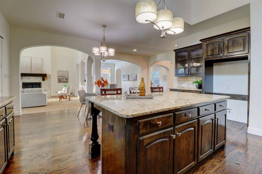 11559 Ashley Lane, Frisco, TX 75035 Kitchen island with a light-toned countertop, dark wood-finish cabinetry, and a ceiling-mounted light fixture