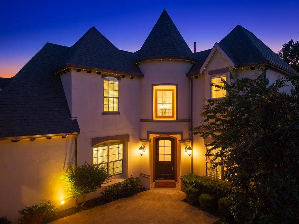 11559 Ashley Lane, Frisco, TX 75035 Stucco exterior with a turretted architectural feature, dark shingles, exterior lighting, and a paneled entry door