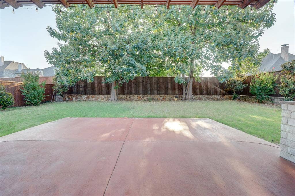 11559 Ashley Lane, Frisco, TX 75035 Expansive backyard featuring a large concrete patio, manicured lawn, and mature trees
