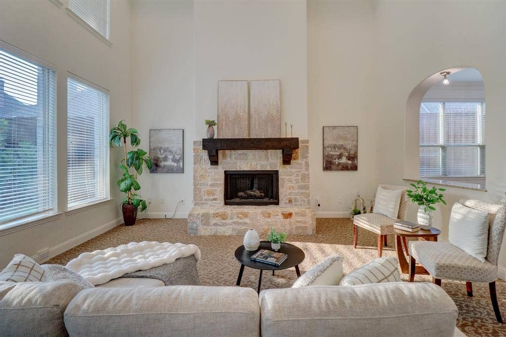 11559 Ashley Lane, Frisco, TX 75035 Two-story living area featuring a stone fireplace with a substantial wood mantel, high vaulted ceilings, and multiple windows
