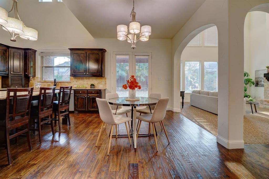 11559 Ashley Lane, Frisco, TX 75035 Hardwood flooring, arched doorways, dark wood cabinetry, built-in breakfast bar, and vaulted ceilings