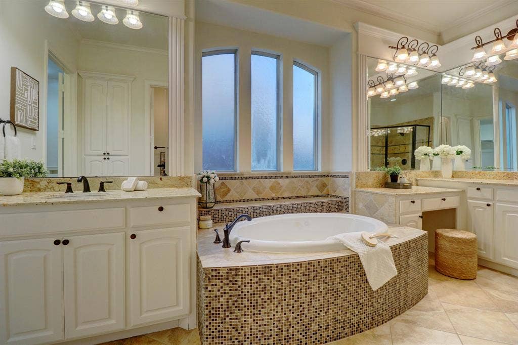 11559 Ashley Lane, Frisco, TX 75035 Dual vanity with integrated sinks and granite countertops, a built-in soaking tub with mosaic tile surround, and a separate vanity area