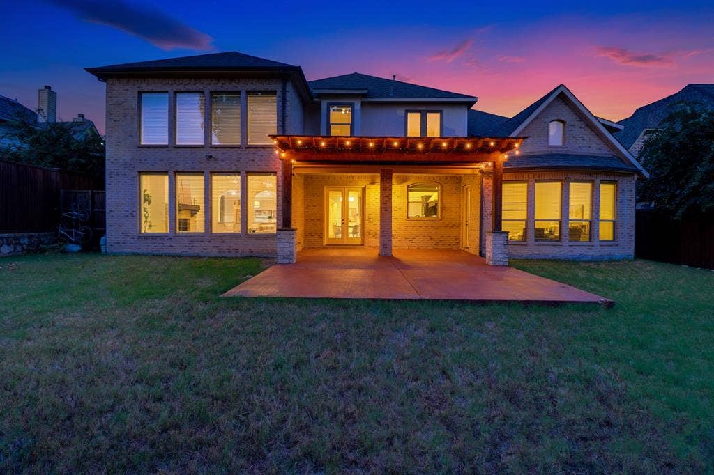 11559 Ashley Lane, Frisco, TX 75035 Brick exterior with multiple large windows, covered patio with wood pergola, and stone-clad columns
