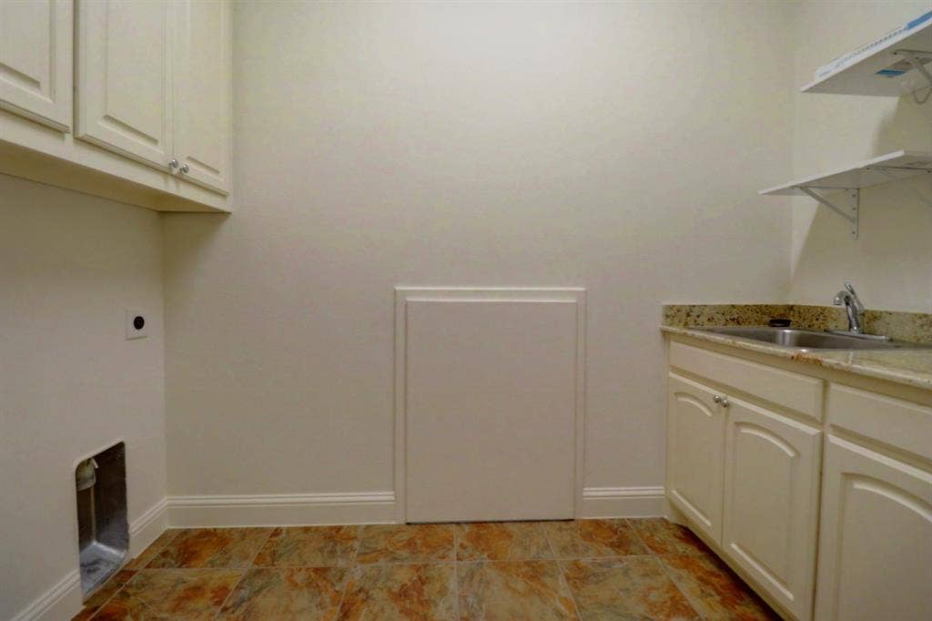 11559 Ashley Lane, Frisco, TX 75035 Utility space featuring upper and lower cabinetry, a stainless steel sink, and a stone-finish countertop