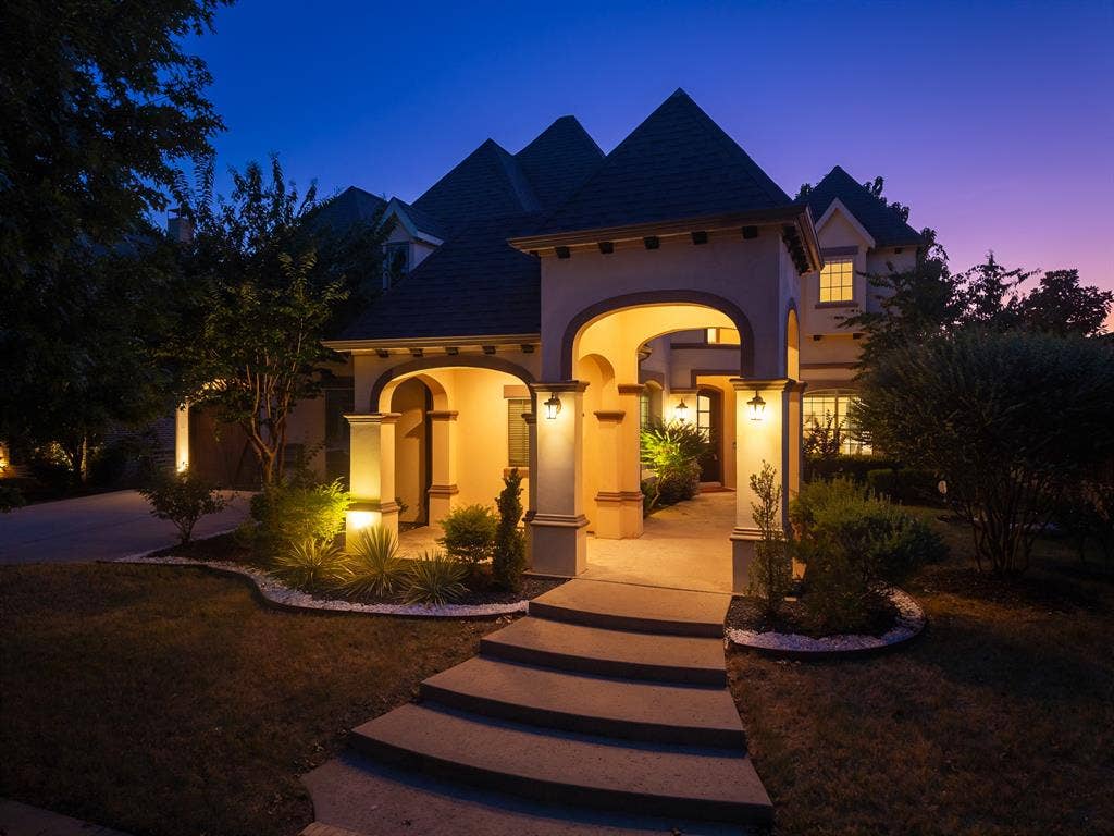 11559 Ashley Lane, Frisco, TX 75035 Stucco exterior featuring arched entryway, concrete step pathway, and mature landscaping with accent lighting