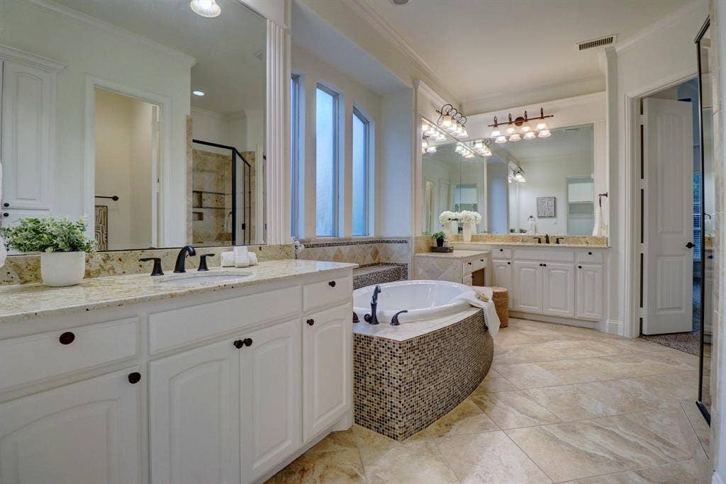 11559 Ashley Lane, Frisco, TX 75035 Built-in soaking tub with mosaic tile surround, two separate vanity stations with white cabinetry, granite countertops, and tile flooring