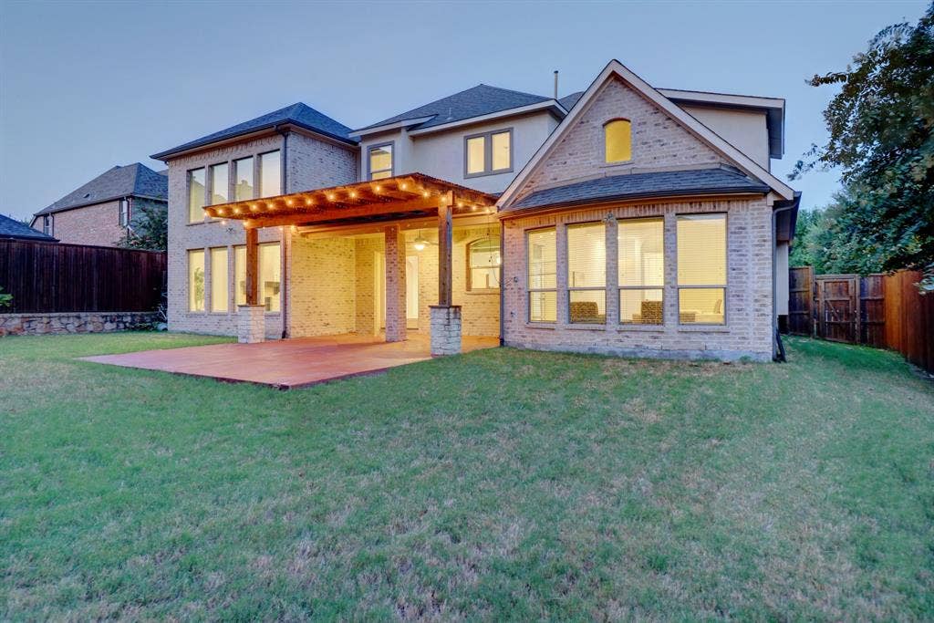 11559 Ashley Lane, Frisco, TX 75035 Expansive backyard featuring a brick exterior, covered patio with a wood pergola, and large windows