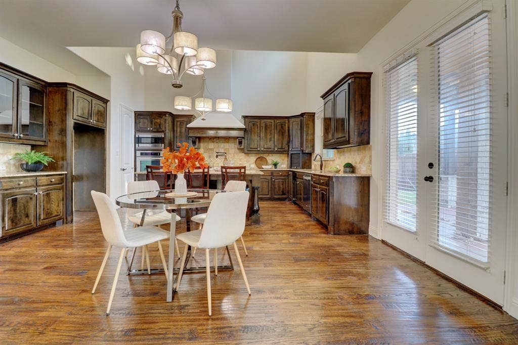 11559 Ashley Lane, Frisco, TX 75035 Kitchen featuring rich wood-finish flooring, dark wood cabinetry, built-in stainless steel appliances, and a central island with a breakfast bar