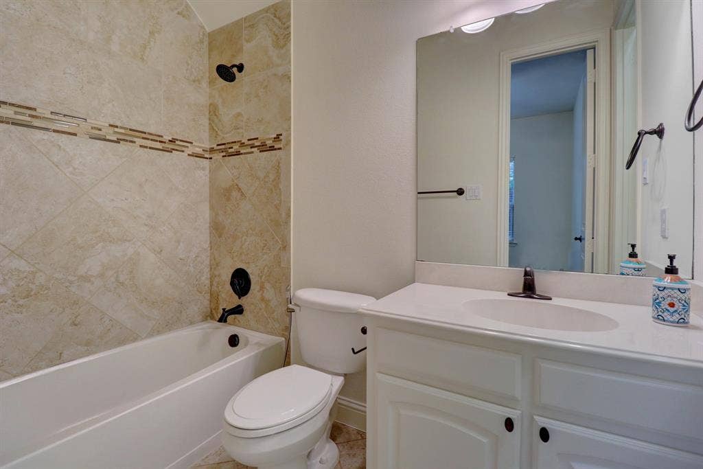 11559 Ashley Lane, Frisco, TX 75035 White vanity with an integrated sink, large mirror, and bronze fixtures