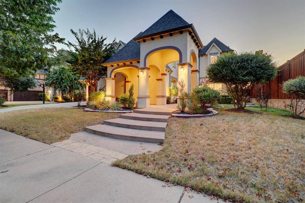 11559 Ashley Lane, Frisco, TX 75035 Stucco exterior with a grand arched entry, dark tile roof, and stone steps