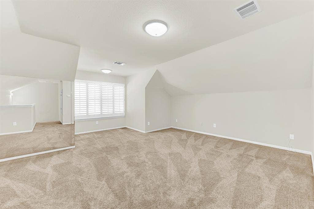3217 Royal Melbourne Drive, Plano, TX 75093 This versatile upper-level bonus room features soft carpeting, warm neutral paint, a mirrored wall section, and a bright window framed by plantation shutters. It offers an ideal setup for a quiet home workout space, private office, or cozy media lounge away from main living areas.